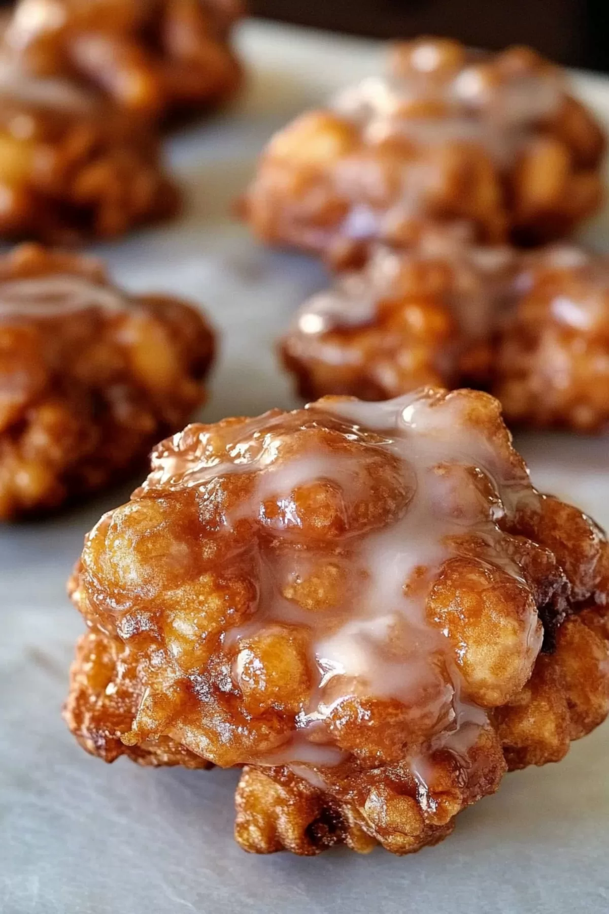 Close-up of a flaky fritter with chunks of apple peeking through the dough.