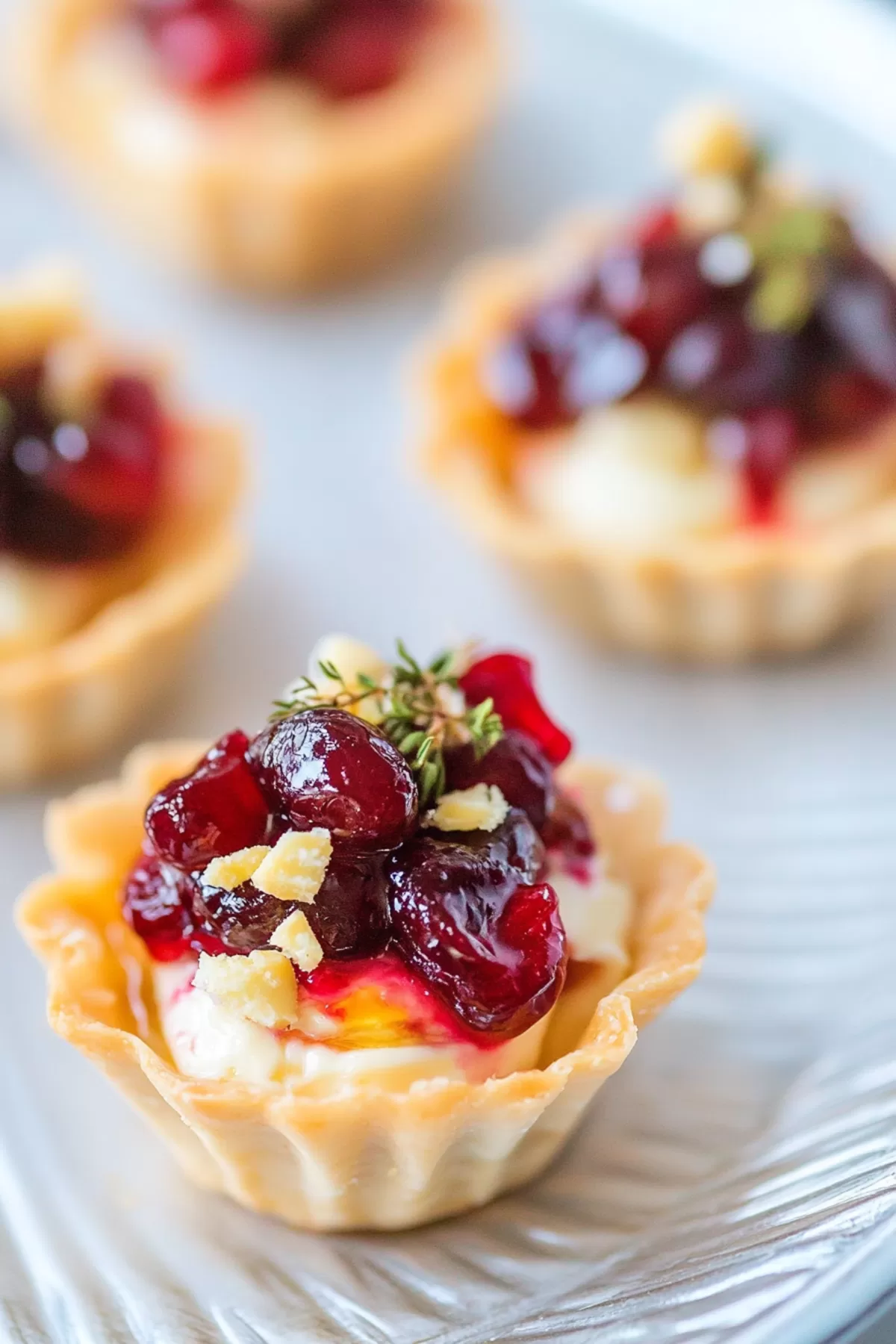 Close-up of a bite-sized appetizer featuring melted brie, tangy cranberry topping, and a crisp shell.