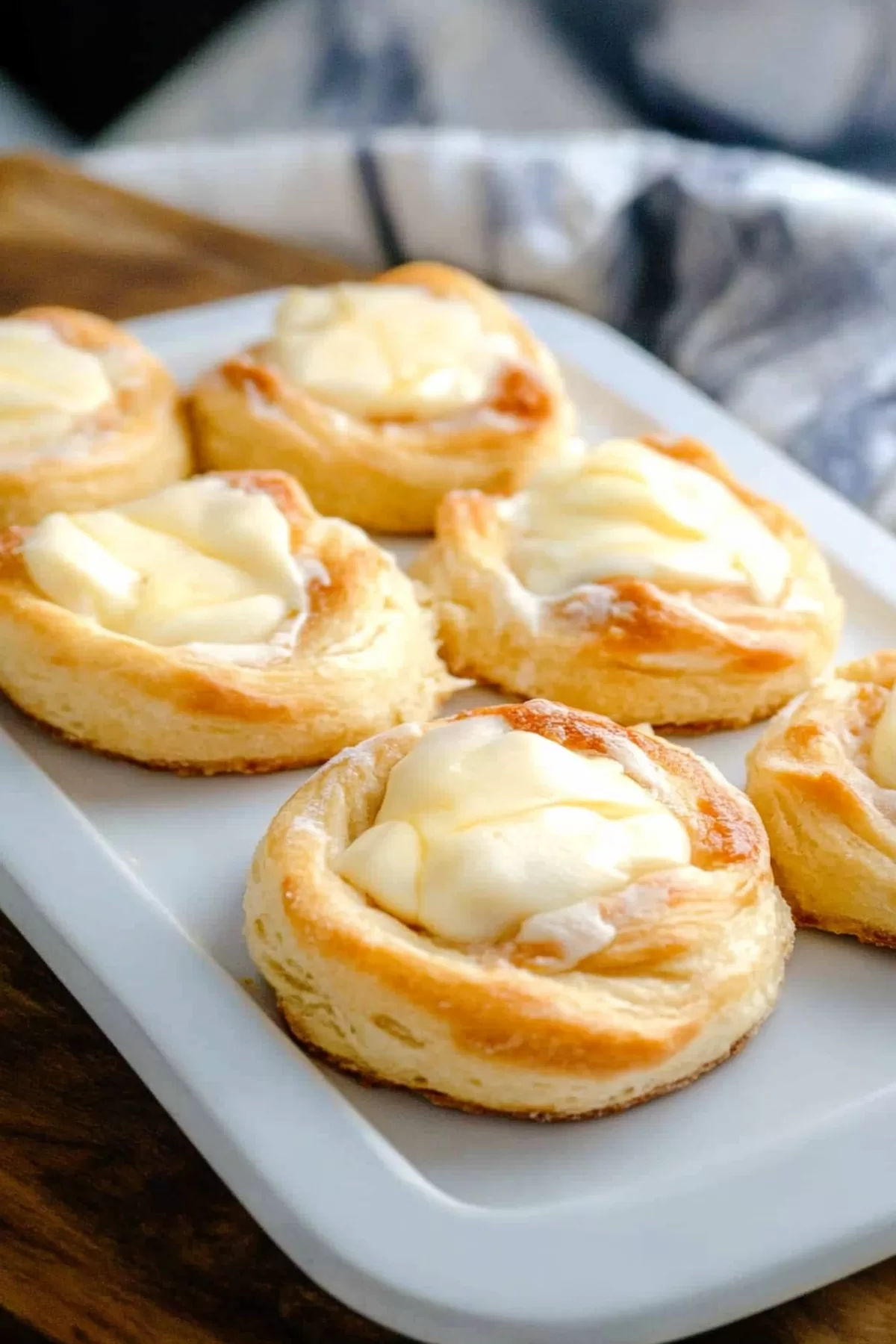 A rustic platter of cheese-filled pastries, garnished with a sprinkle of powdered sugar.