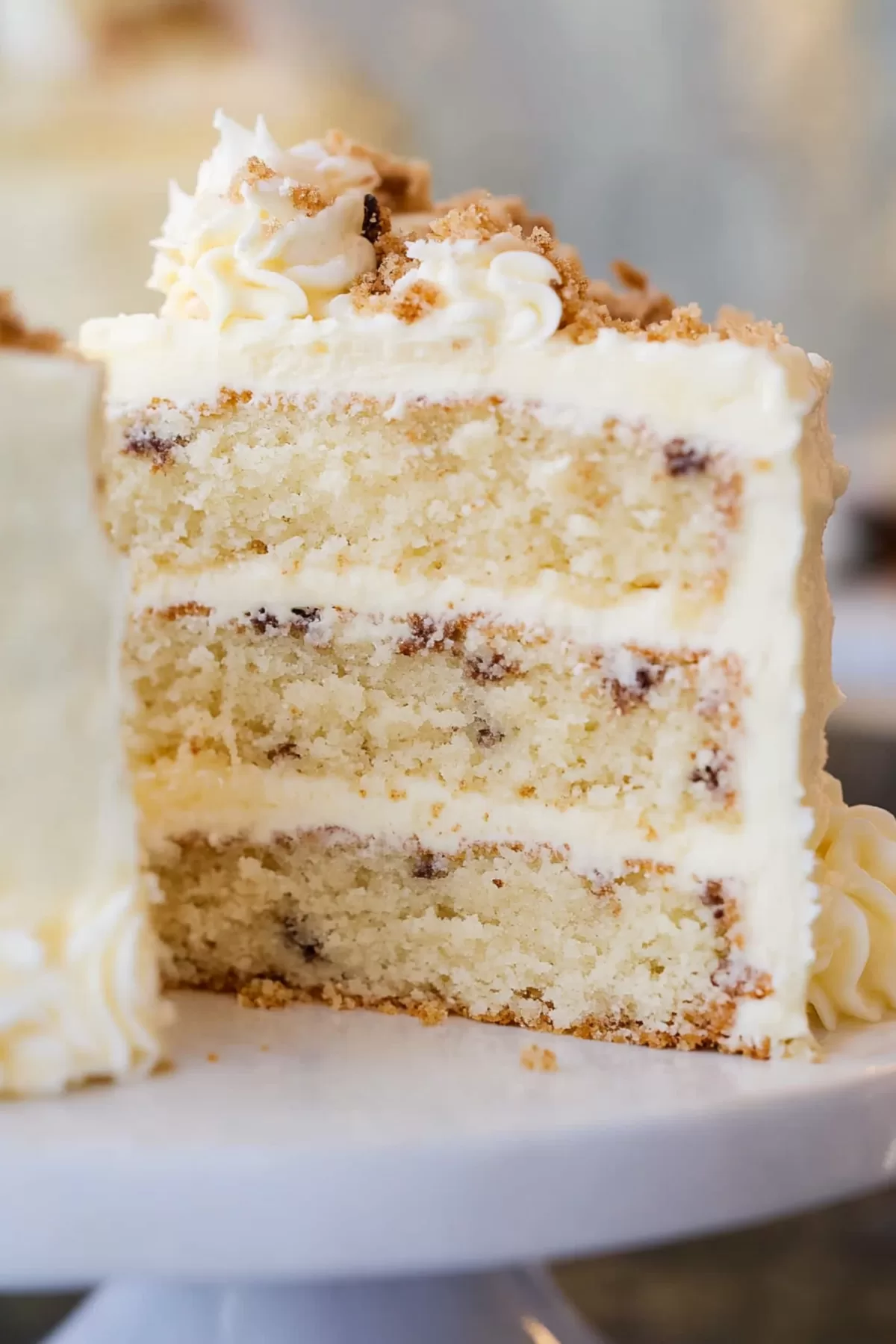 A slice of moist layer cake topped with creamy frosting and a sprinkle of chopped nuts.