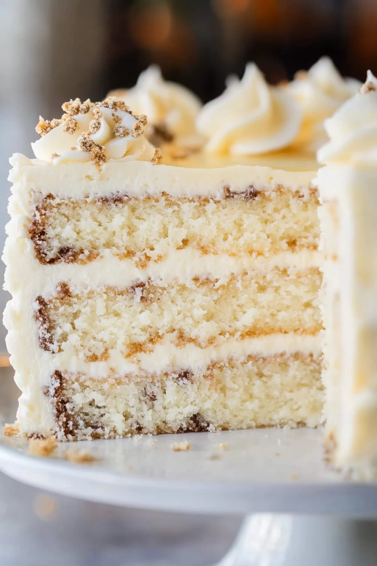 A plated slice of cake with delicate frosting details and a garnish of nuts.