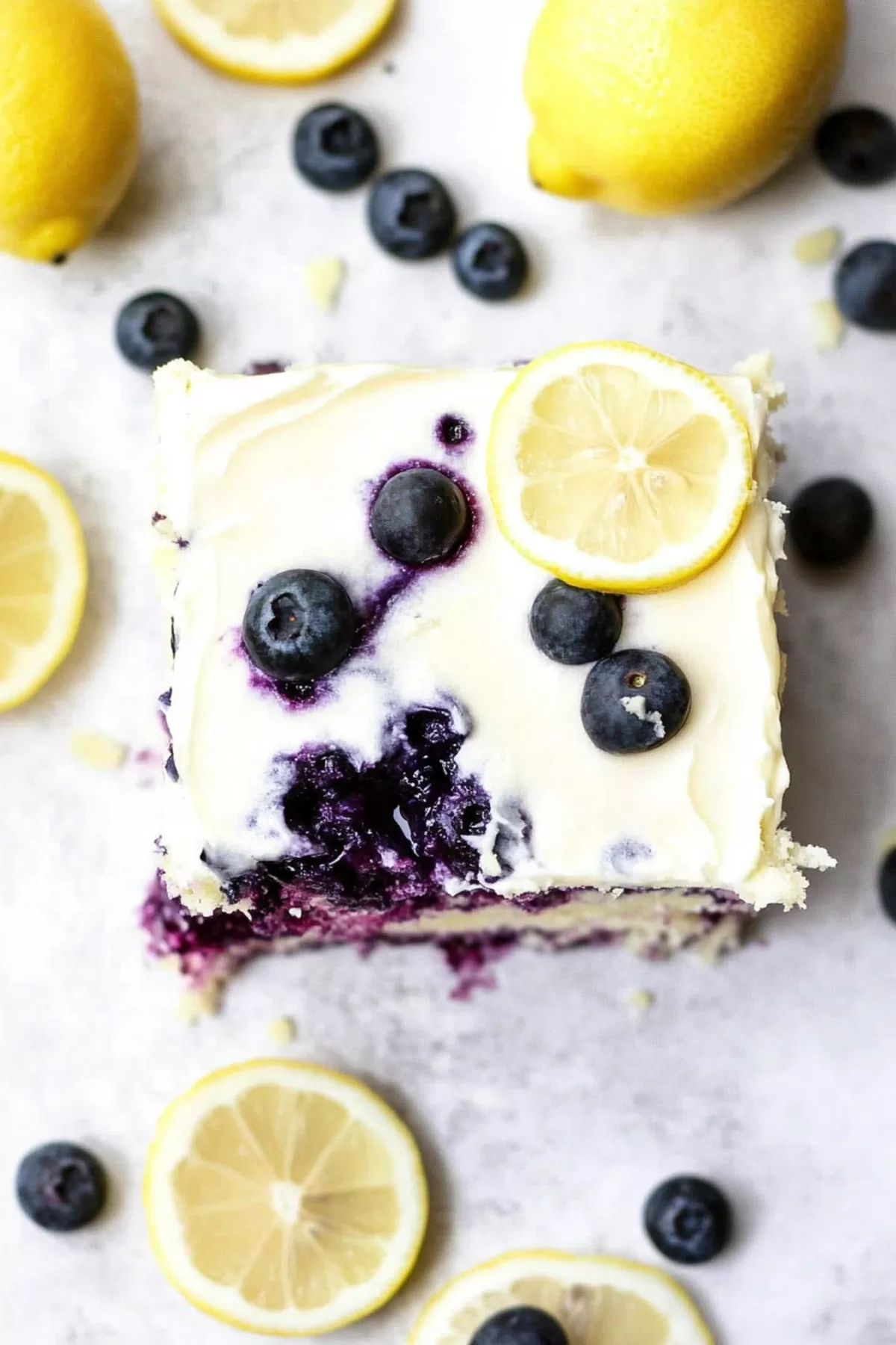 Overhead view of a frosted sheet cake decorated with fresh blueberries and lemon slices.