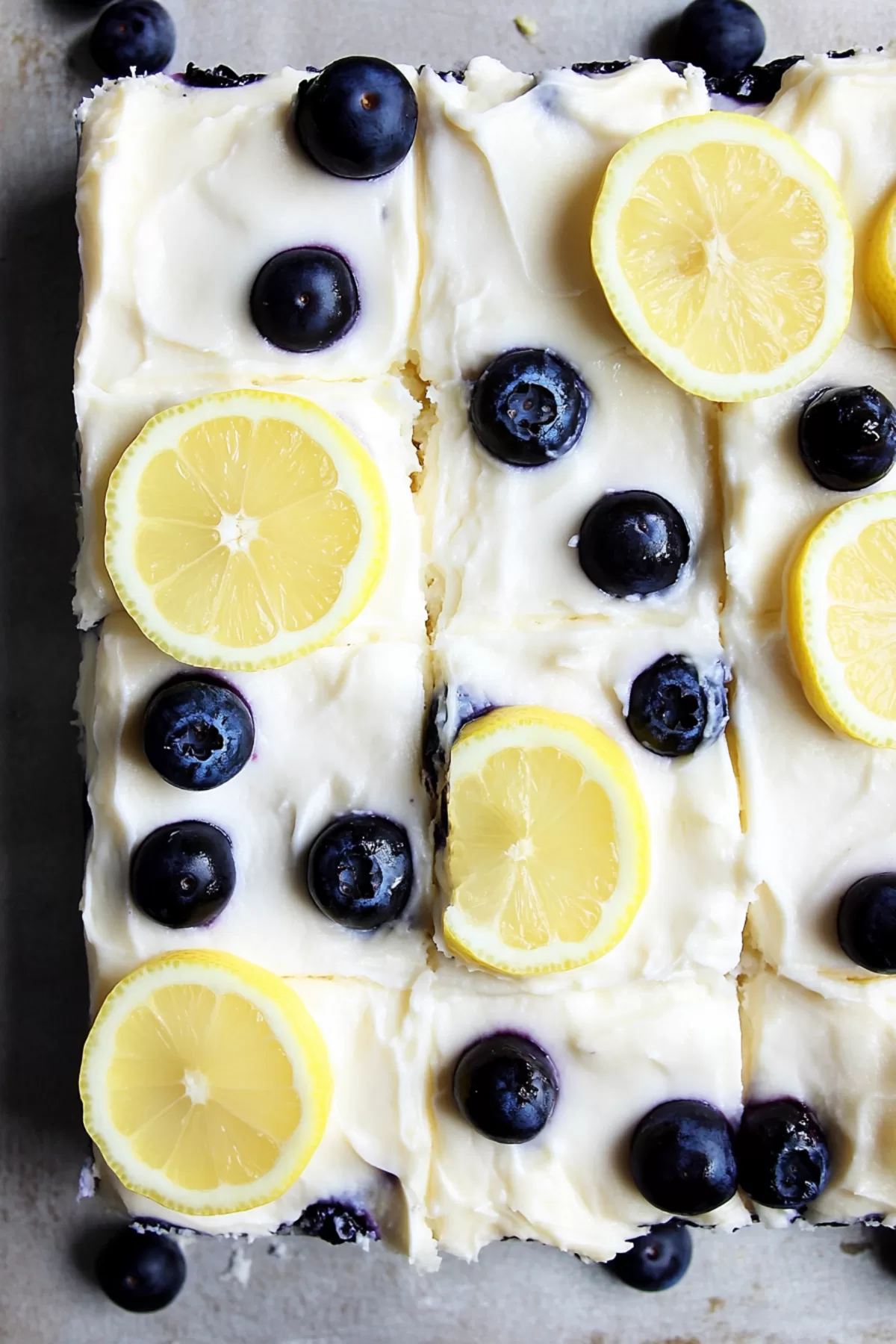 Bright and zesty cake topped with creamy frosting, blueberries, and lemon slices for garnish.