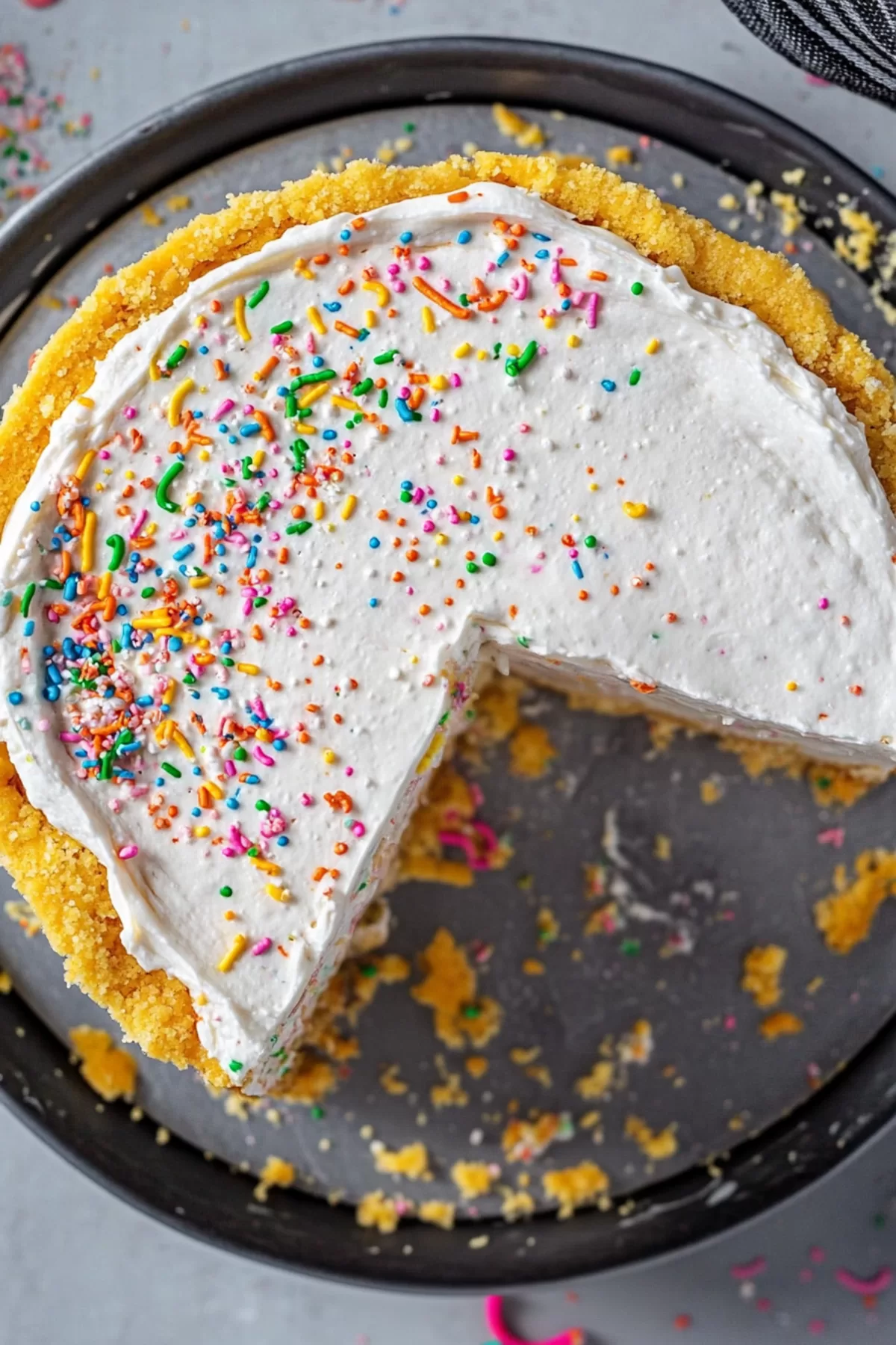 Close-up of a slice of creamy cheesecake with festive rainbow sprinkles.