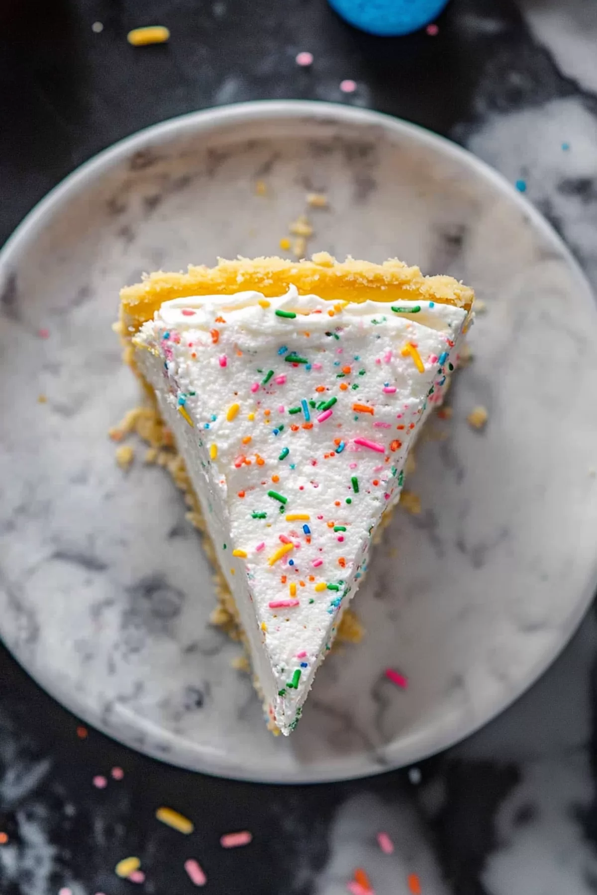 A celebratory cheesecake with layers of color and a decorative sprinkle topping.