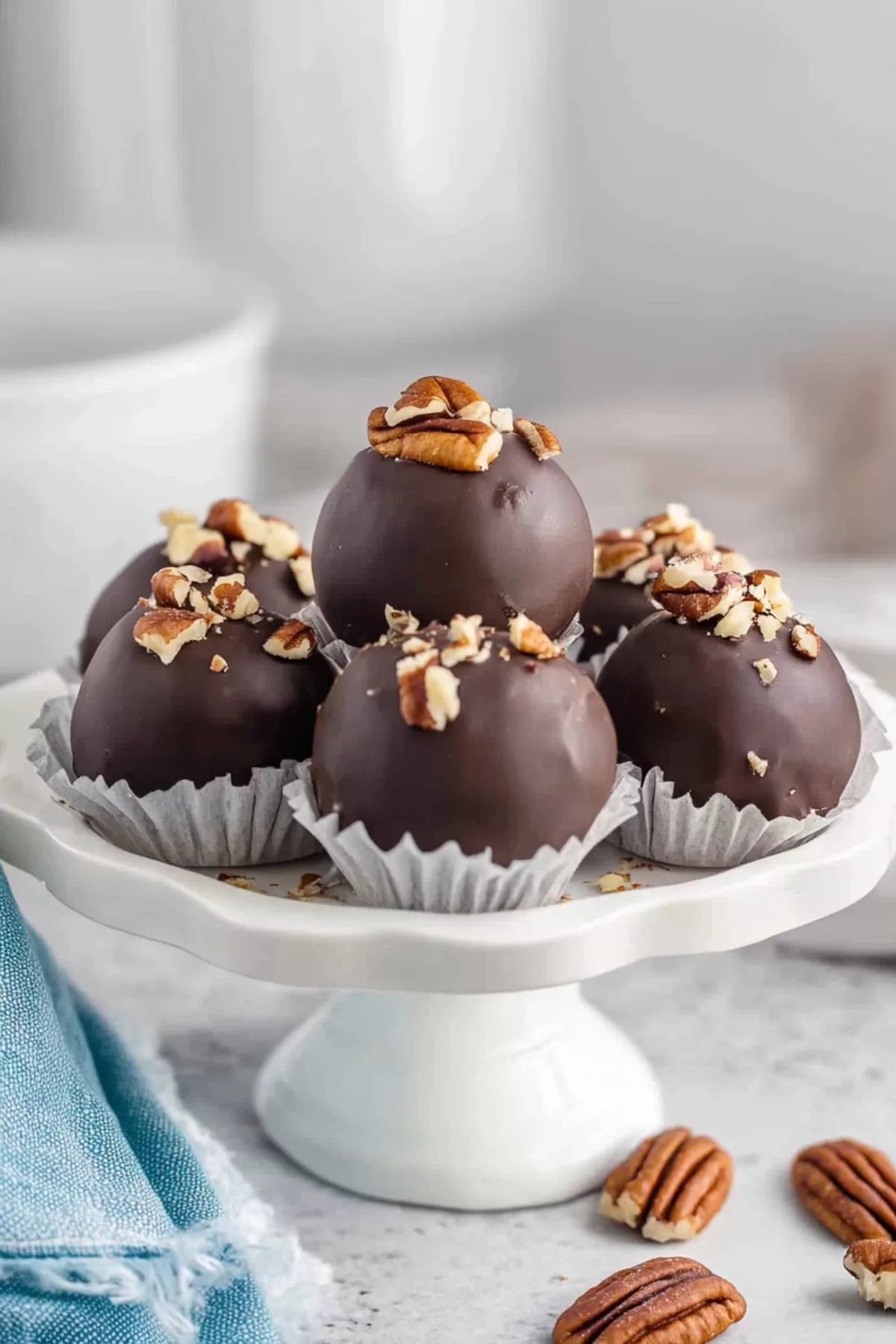 Handmade dessert balls featuring a glossy chocolate exterior and pecan garnish.