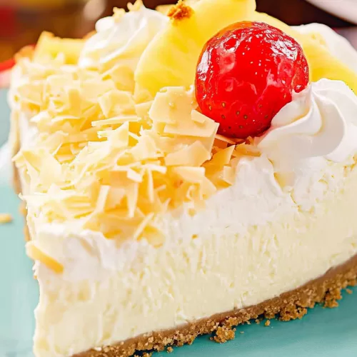 A close-up of a creamy Pina Colada pie slice topped with whipped cream, fresh pineapple chunks, and a maraschino cherry.