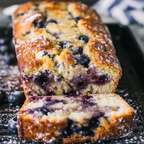 A close-up shot of the loaf showcasing its soft texture and bright blueberry studded layers.