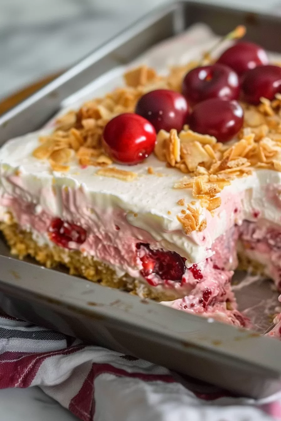 Rich and creamy cherry cheesecake lush garnished with whole cherries and almond crumbs.