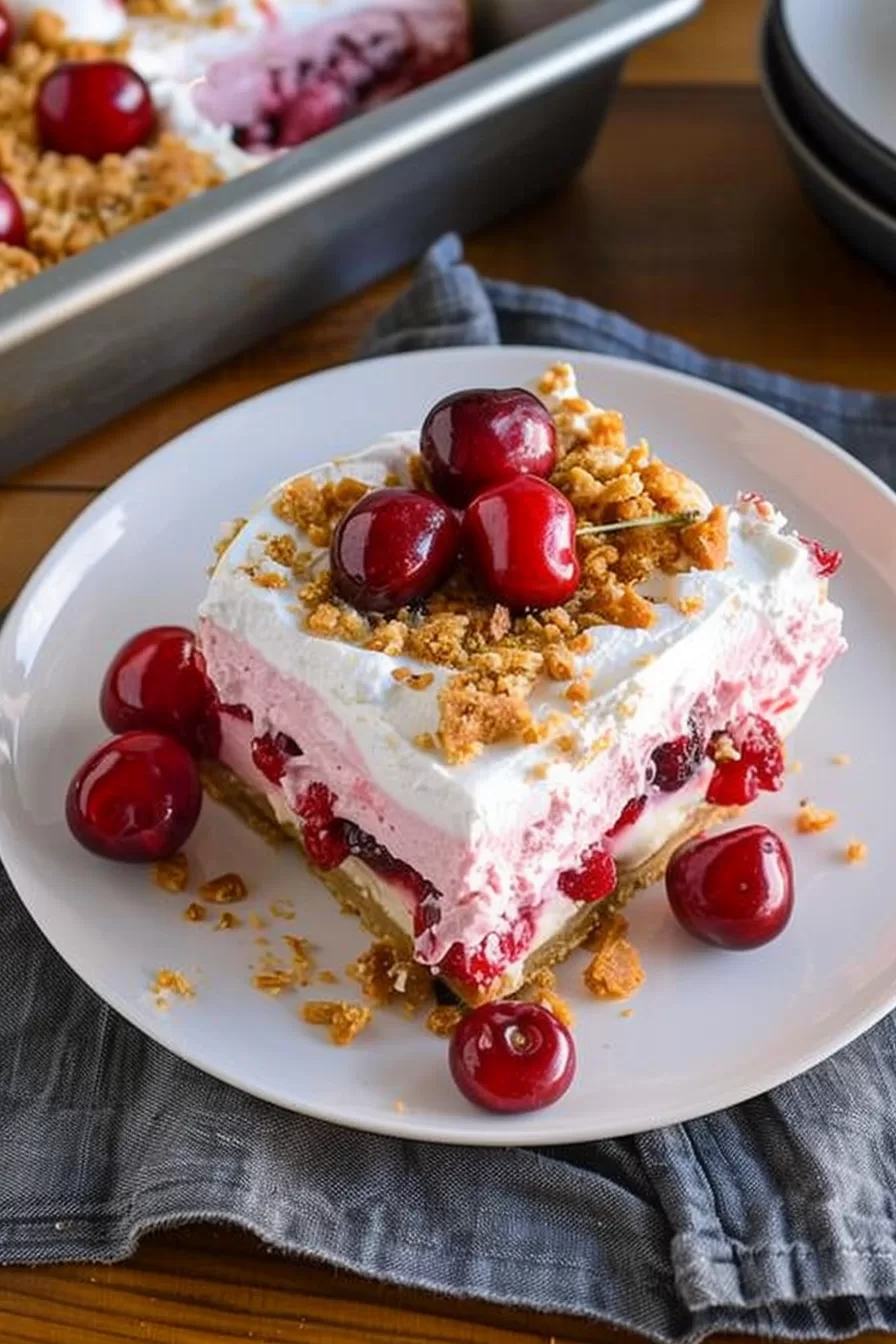 Layered cherry cheesecake lush in a pan, highlighting the creamy and fruity textures.