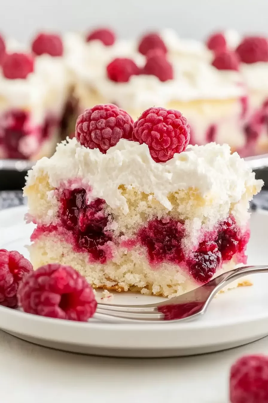 A single slice of raspberry poke cake on a plate, showcasing the rich layers of raspberry and coconut.