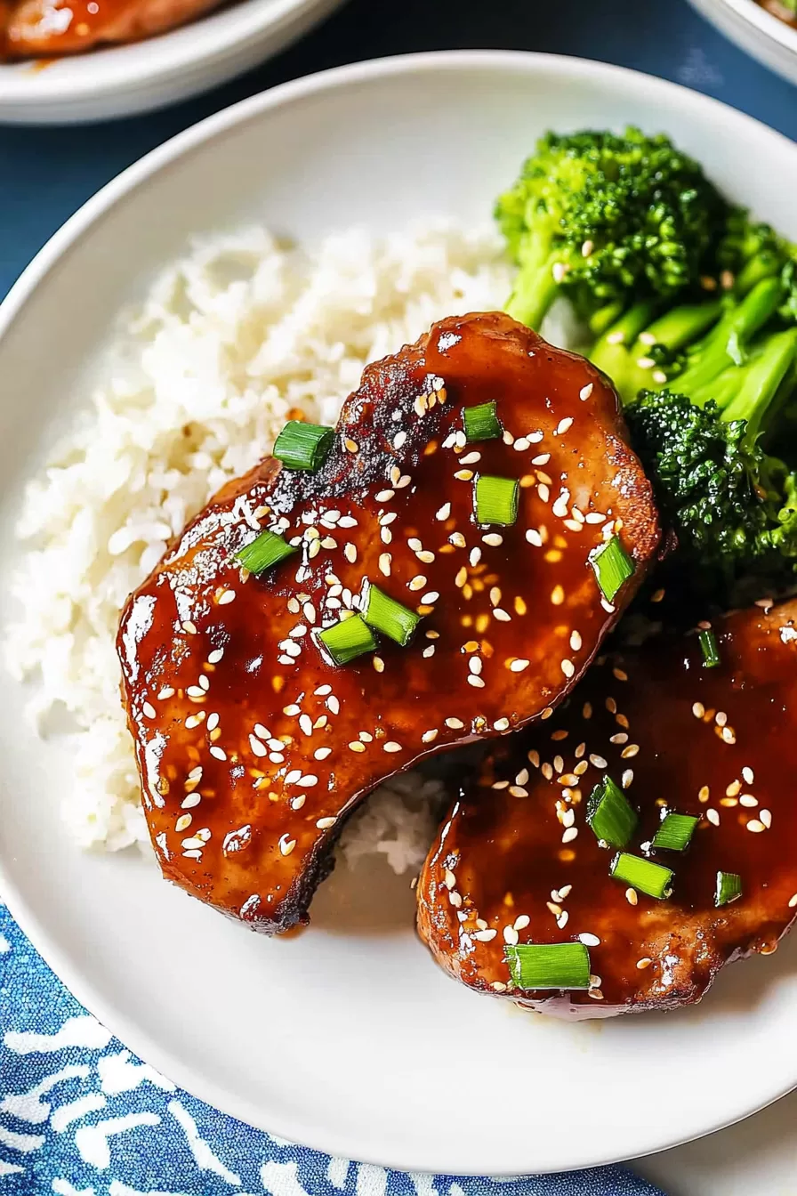 Plate of tender pork chops with a glossy honey garlic glaze, served over fluffy white rice and a side of vibrant green broccoli.