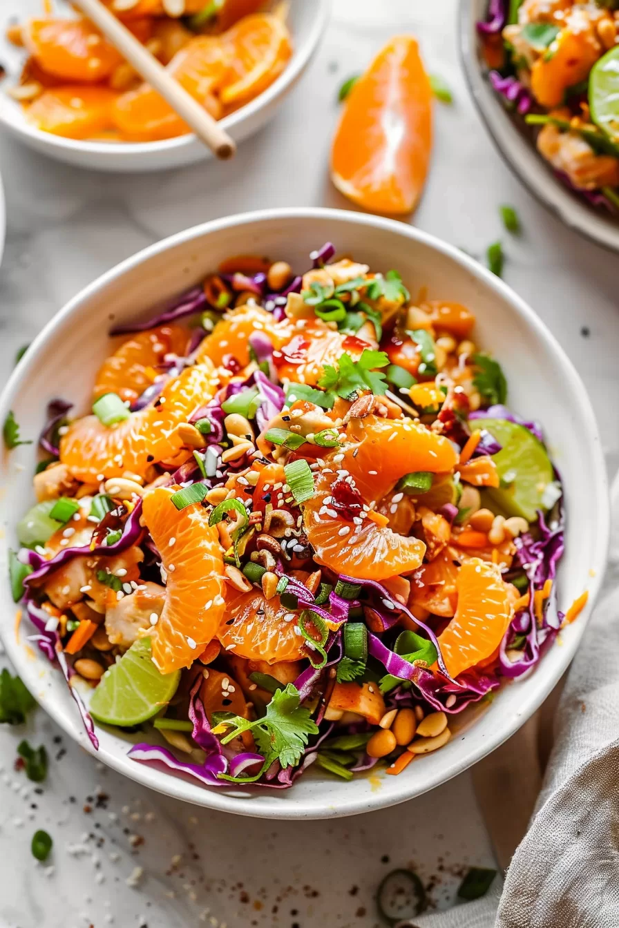 Overhead shot of a refreshing Mandarin Orange Chicken Salad garnished with fresh herbs, nuts, and a medley of vegetables.