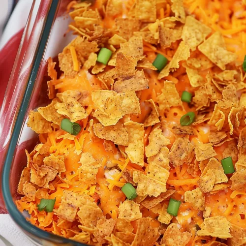 Top view of a casserole dish filled with colorful, cheesy Mexican-inspired chicken casserole, garnished with fresh green onions.