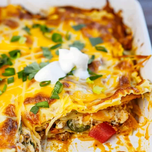 A baking dish filled with colorful Mexican lasagna featuring vibrant toppings like diced tomatoes and green onions.