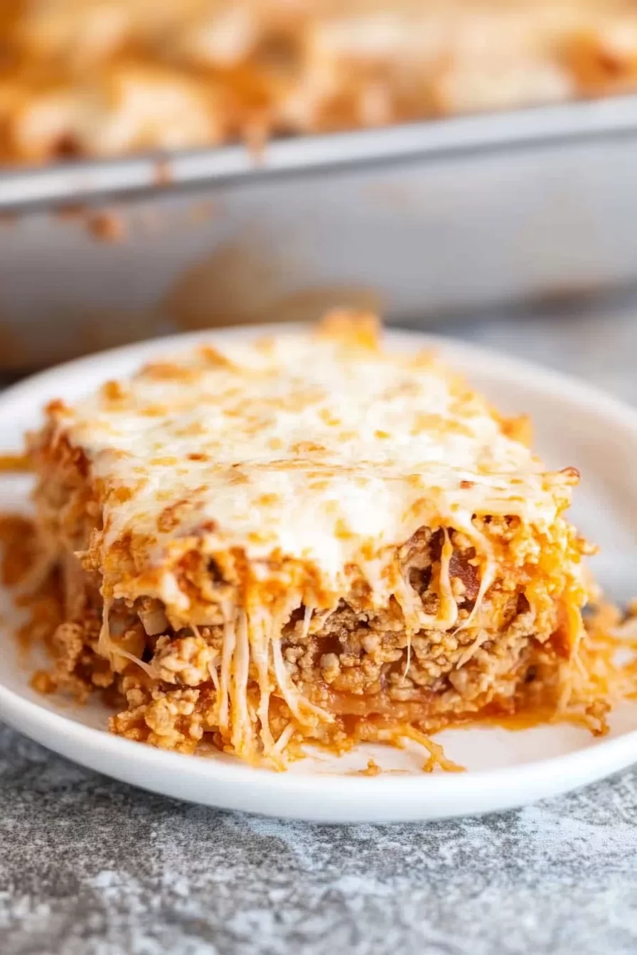 Close-up of a plate with a generous serving of spaghetti casserole, featuring a rich meat sauce and creamy layers.