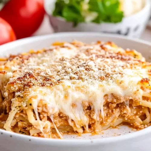 Bubbly, golden-topped spaghetti casserole garnished with a sprinkle of fresh herbs, ready to serve.