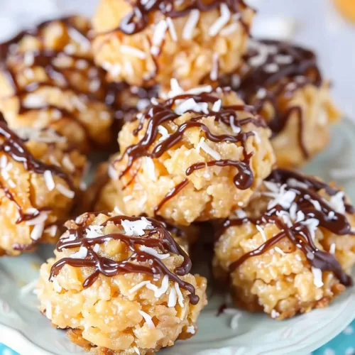 A white serving plate showcasing a cluster of caramel-dipped coconut macaroons with a glossy chocolate finish.