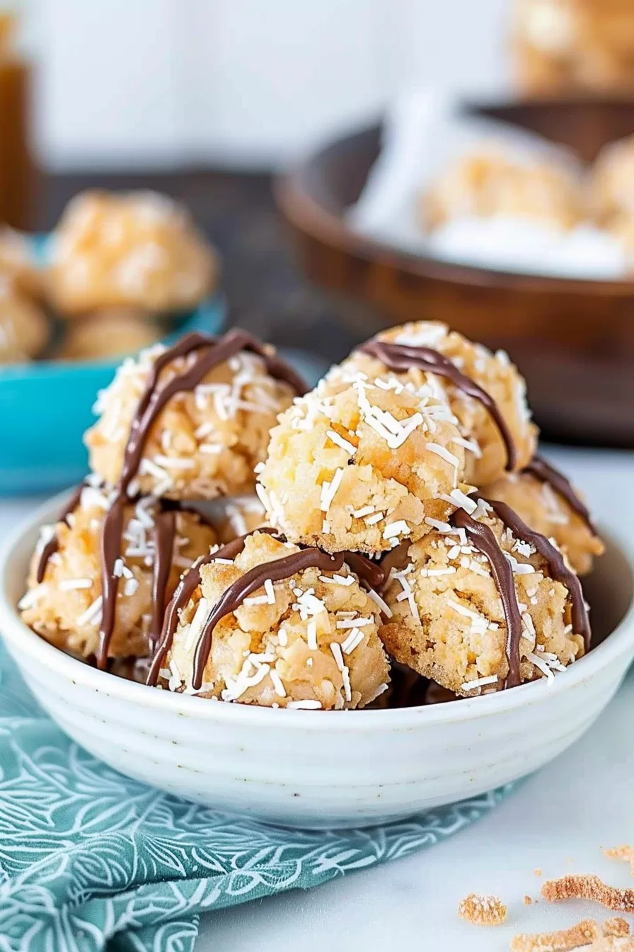 A rustic bowl filled with coconut macaroons coated in caramel and garnished with shredded coconut and chocolate.