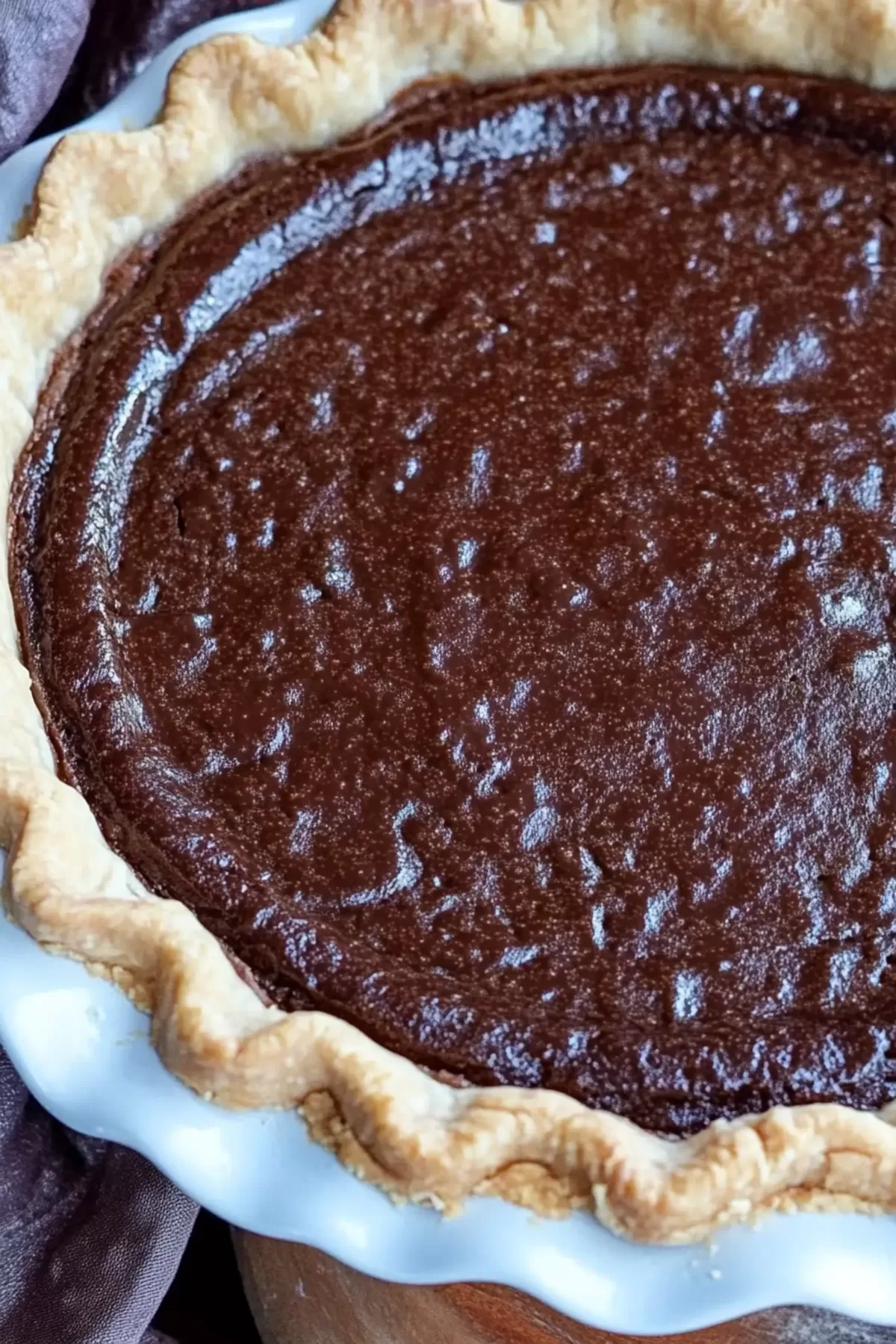 A whole chocolate cream pie in a flaky crust, glistening under natural light.