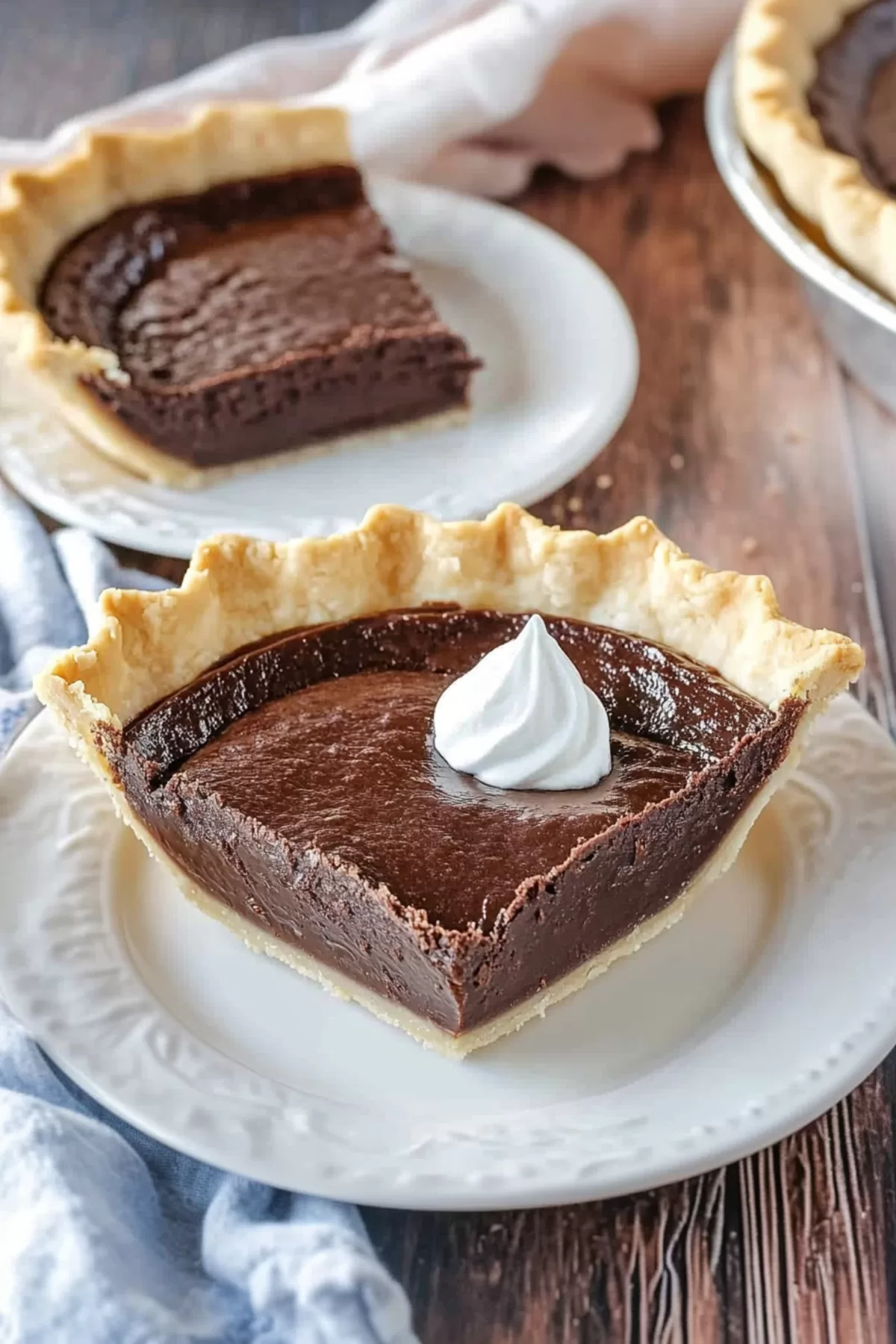 A slice of chocolate cream pie with a golden crust served on a rustic wooden table.