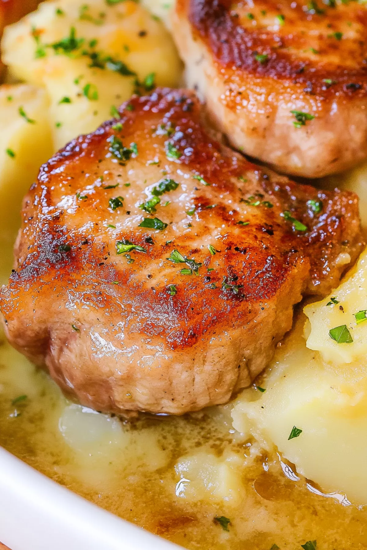 Two succulent pork chops nestled in a sea of buttery scalloped potatoes, highlighted by a golden crust and fresh herbs.