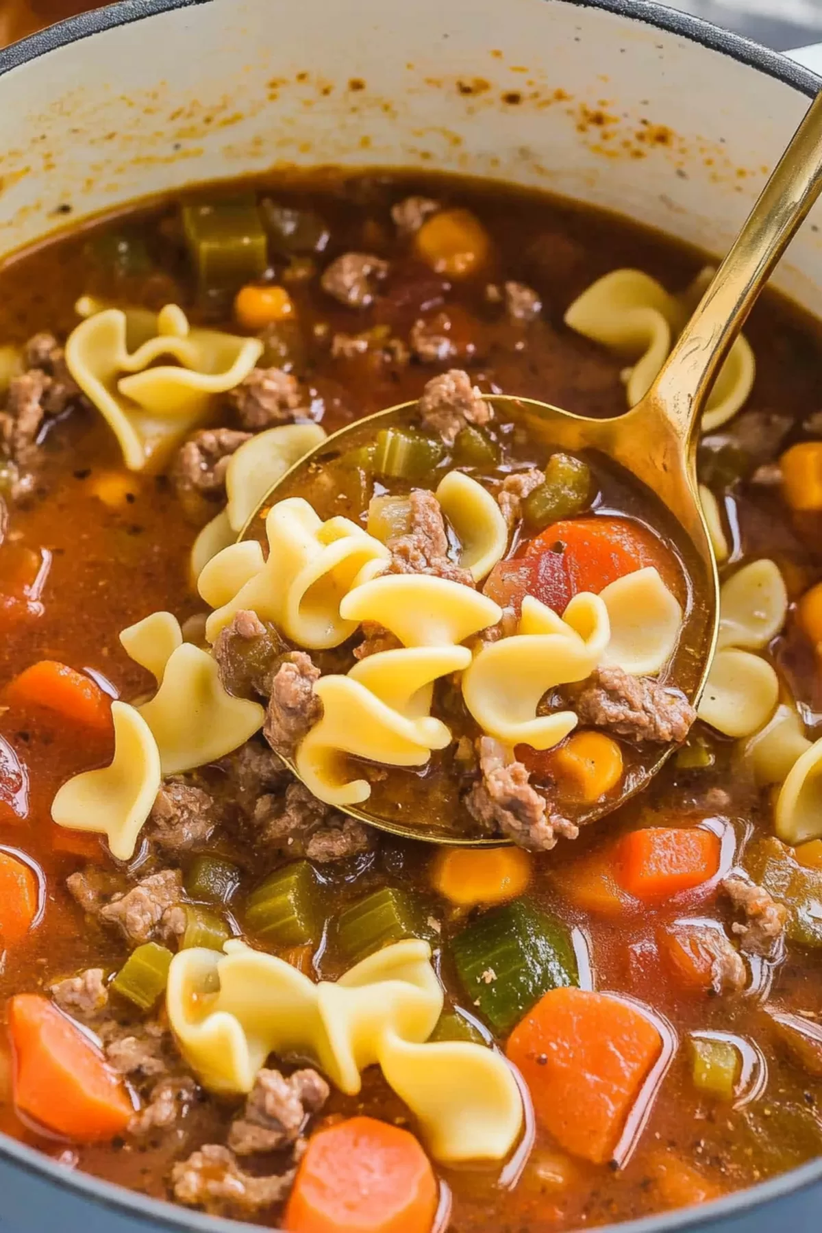 A ladle scooping hearty vegetable beef noodle soup with colorful vegetables and tender beef.