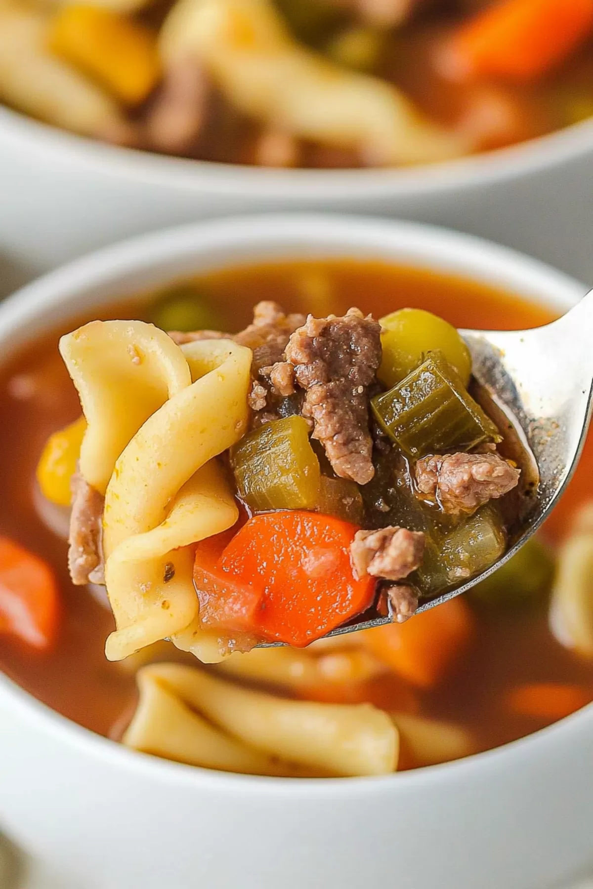 Freshly cooked vegetable beef noodle soup in a white bowl, garnished with parsley for a pop of green.