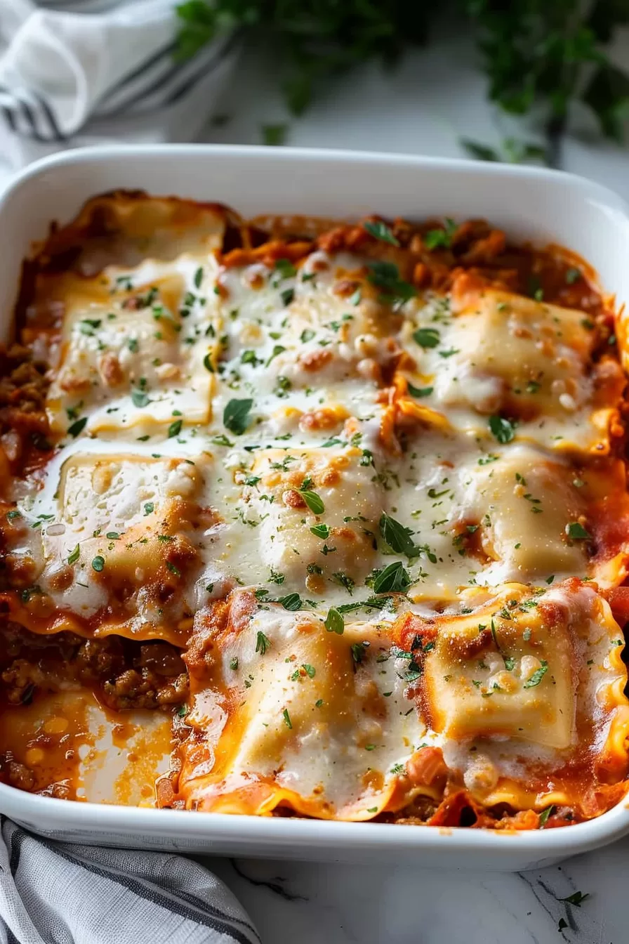 Freshly baked ravioli casserole served in a white ceramic dish, showcasing golden-brown cheese and a hearty meat sauce.