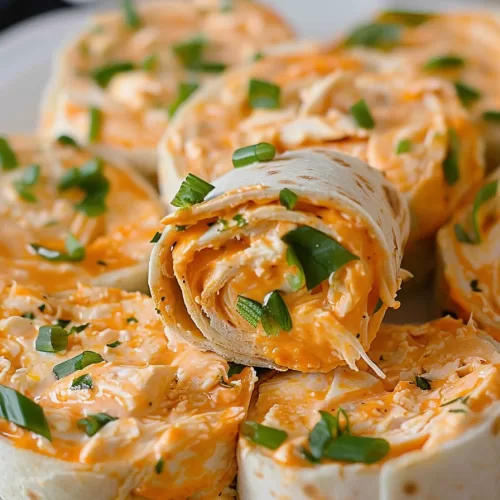 A close-up view of creamy Buffalo Chicken Pinwheels, garnished with fresh parsley on a white plate.