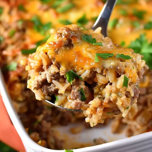 A hearty serving of cheesy ground beef and rice casserole on a spoon, with layers of seasoned beef, rice, and melted cheese visible.