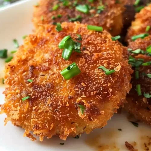 A plate of golden brown chicken fritters with a crunchy breadcrumb coating, sprinkled with fresh parsley.