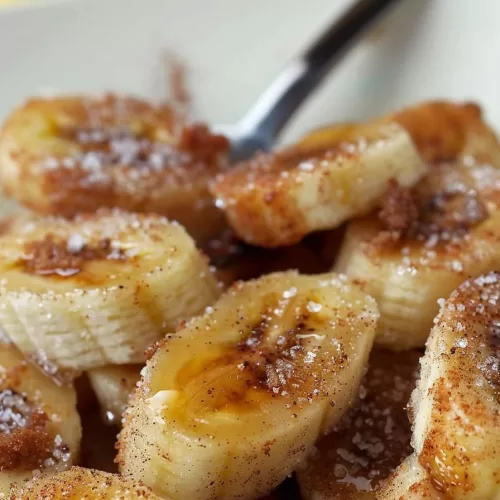 Sweet cinnamon-coated banana slices with a drizzle of syrup in a bowl.