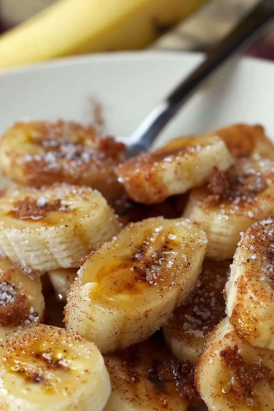 Sweet cinnamon-coated banana slices with a drizzle of syrup in a bowl.