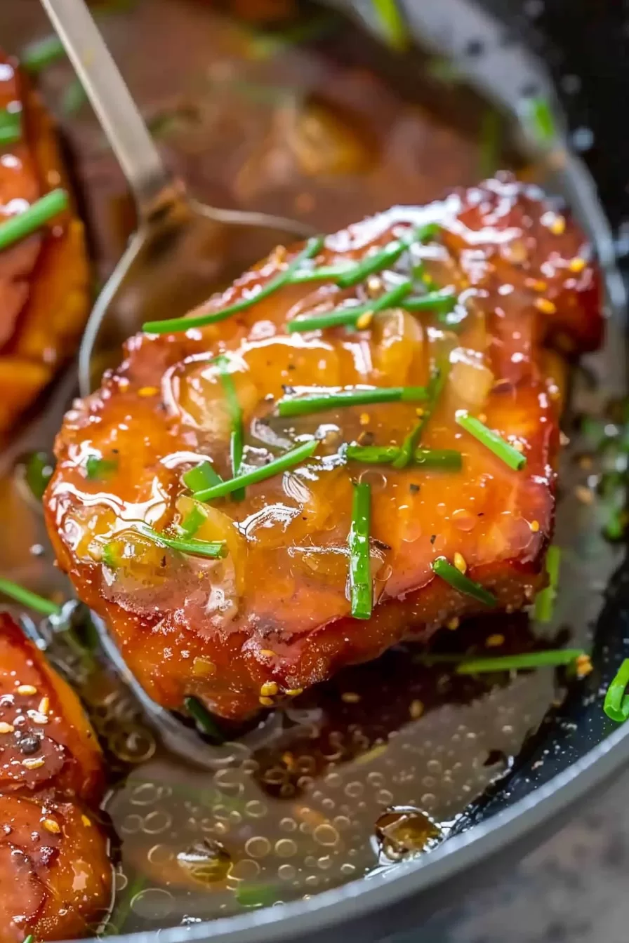 A serving of pork chops with a caramelized honey garlic glaze, sprinkled with herbs for a fresh finish.