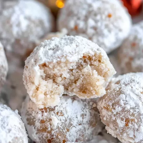 A holiday dessert spread featuring snowball cookies, dusted generously with powdered sugar, alongside festive decorations.