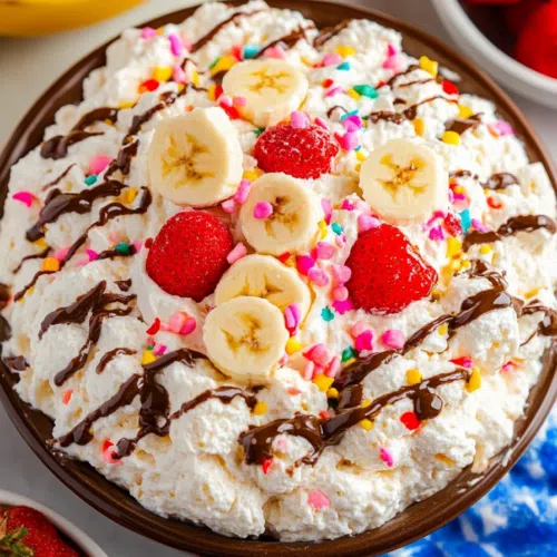 A luscious whipped cream salad loaded with fresh fruits, chocolate, and colorful candy bits for a fun presentation.