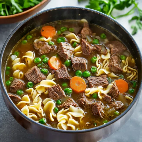 Overhead shot of a bowl of beef noodle soup garnished with fresh herbs.