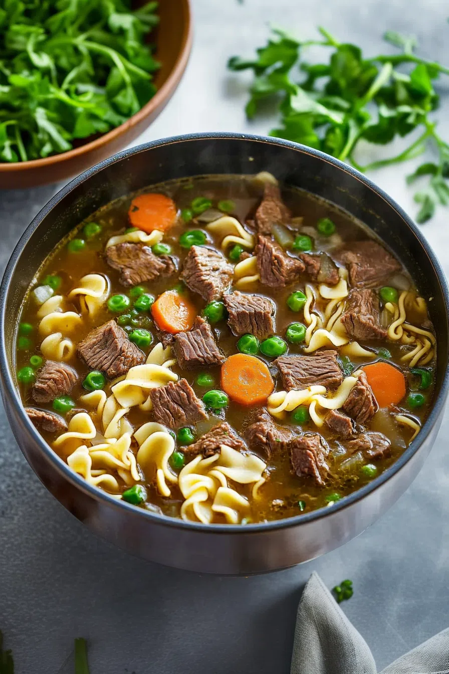 Overhead shot of a bowl of beef noodle soup garnished with fresh herbs.