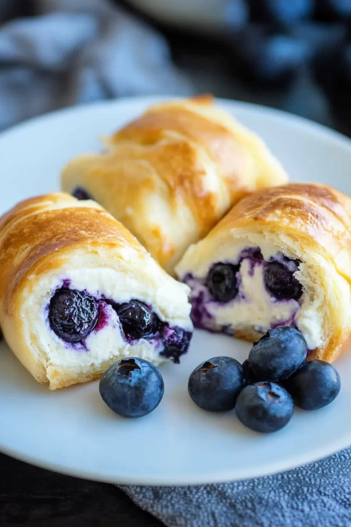 A stack of cheesecake-filled rolls highlighting the soft, golden texture and fresh blueberries.