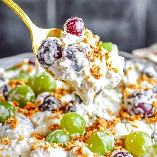 A spoonful of creamy grape salad with visible pecans and grape halves.