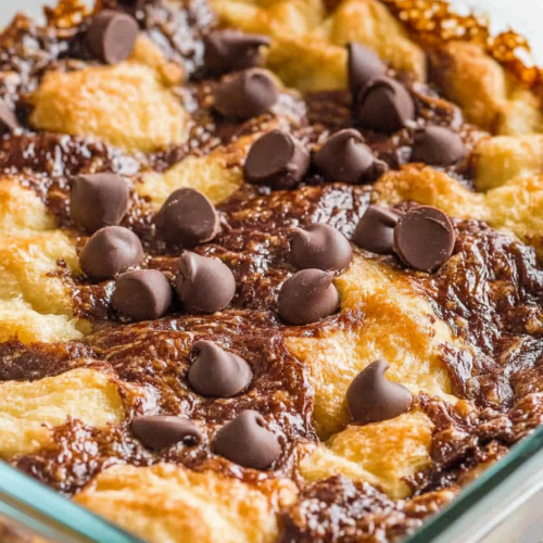 A dish of chocolate croissant breakfast bake, with golden-brown croissant pieces and melted chocolate swirls.