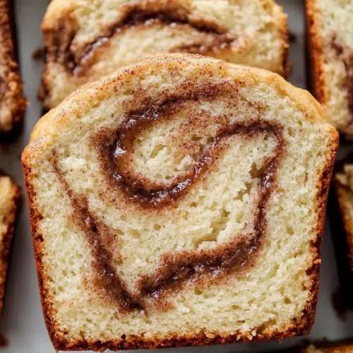 Overhead shot of sliced cinnamon bread on a wooden cutting board, highlighting its texture.