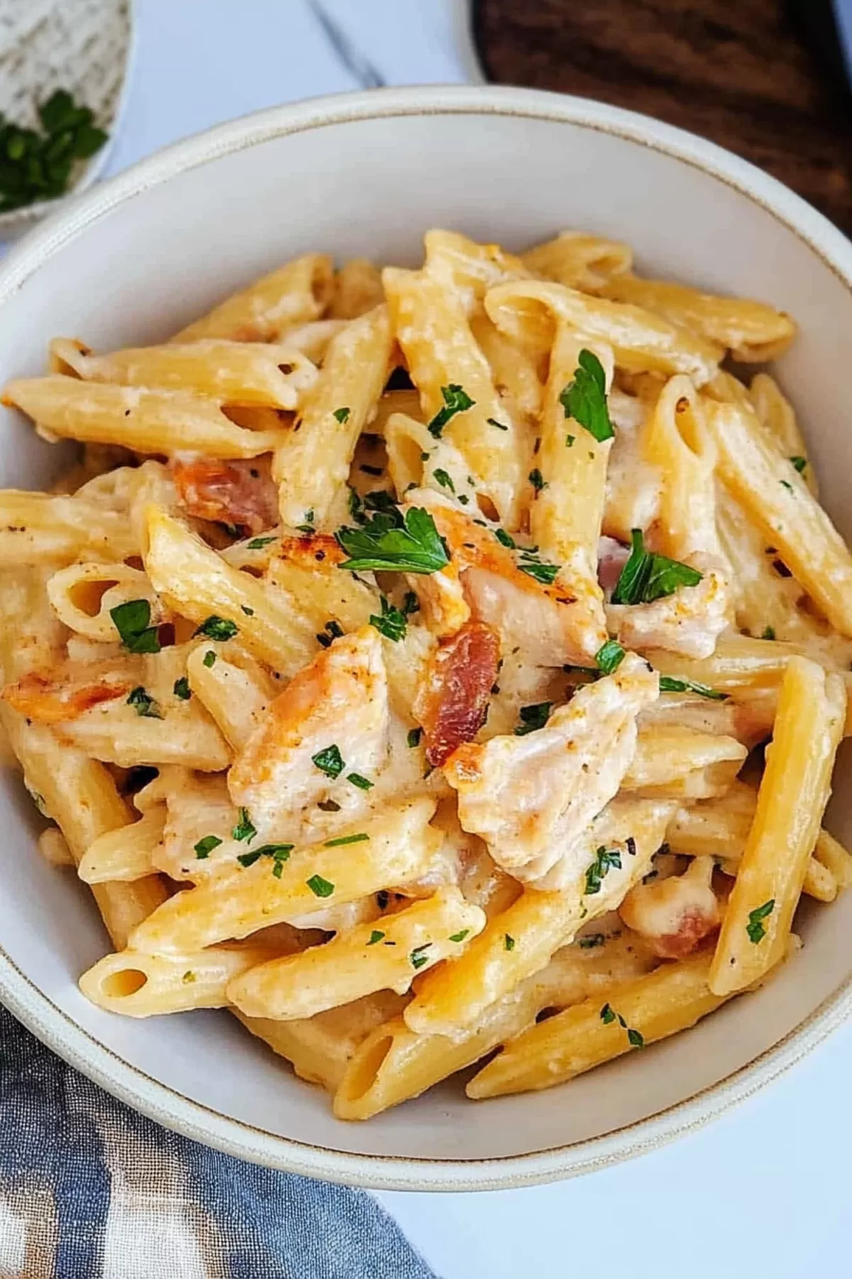 A bowl of hearty pasta with creamy sauce, chicken, and melted cheese.