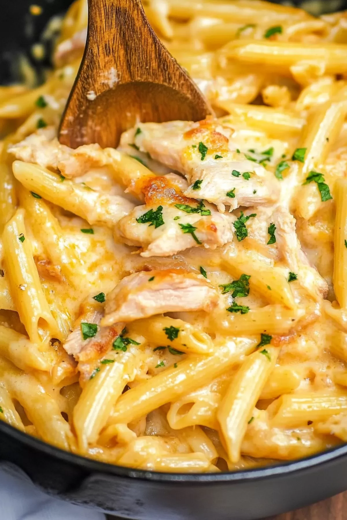 Close-up of penne pasta coated in a savory sauce, topped with crumbled bacon.