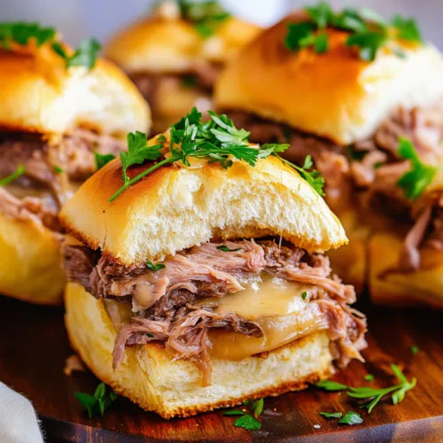 Juicy sliders with melted cheese, served on a toasted bun with a side of au jus.