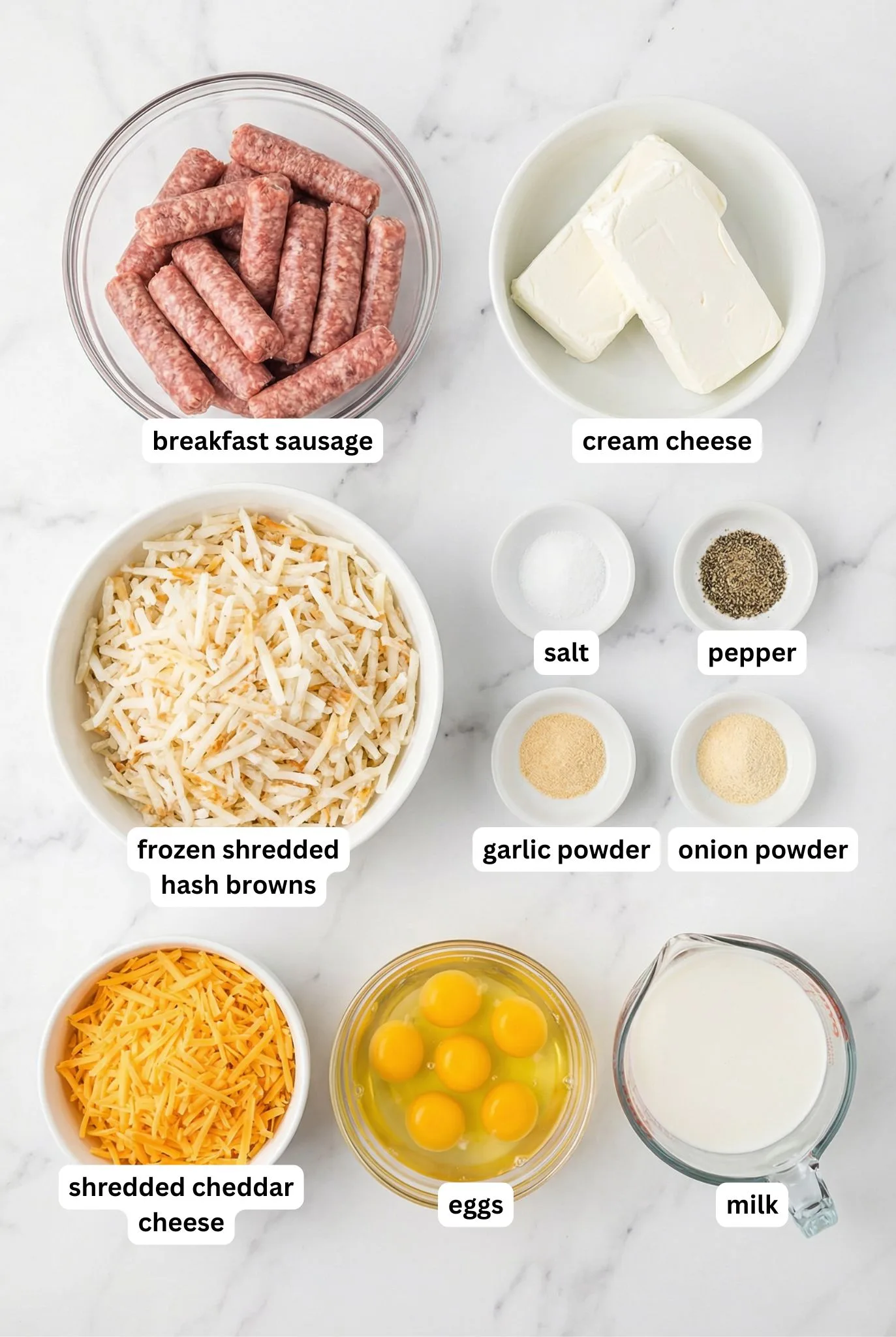 Flat lay of breakfast sausage, cream cheese, frozen hash browns, shredded cheddar, eggs, milk, and seasonings arranged for a Sausage and Cream Cheese Hash Brown Breakfast Casserole