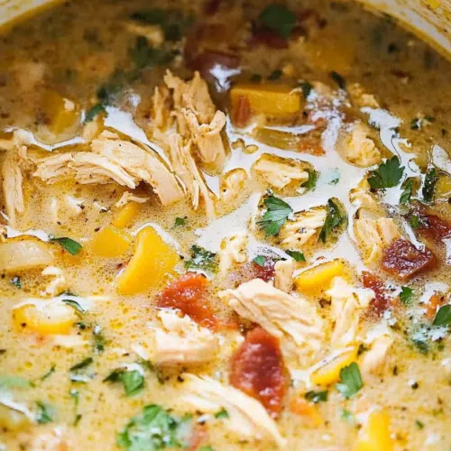 The soup in a white bowl, topped with a sprinkle of shredded cheese and a dollop of sour cream.