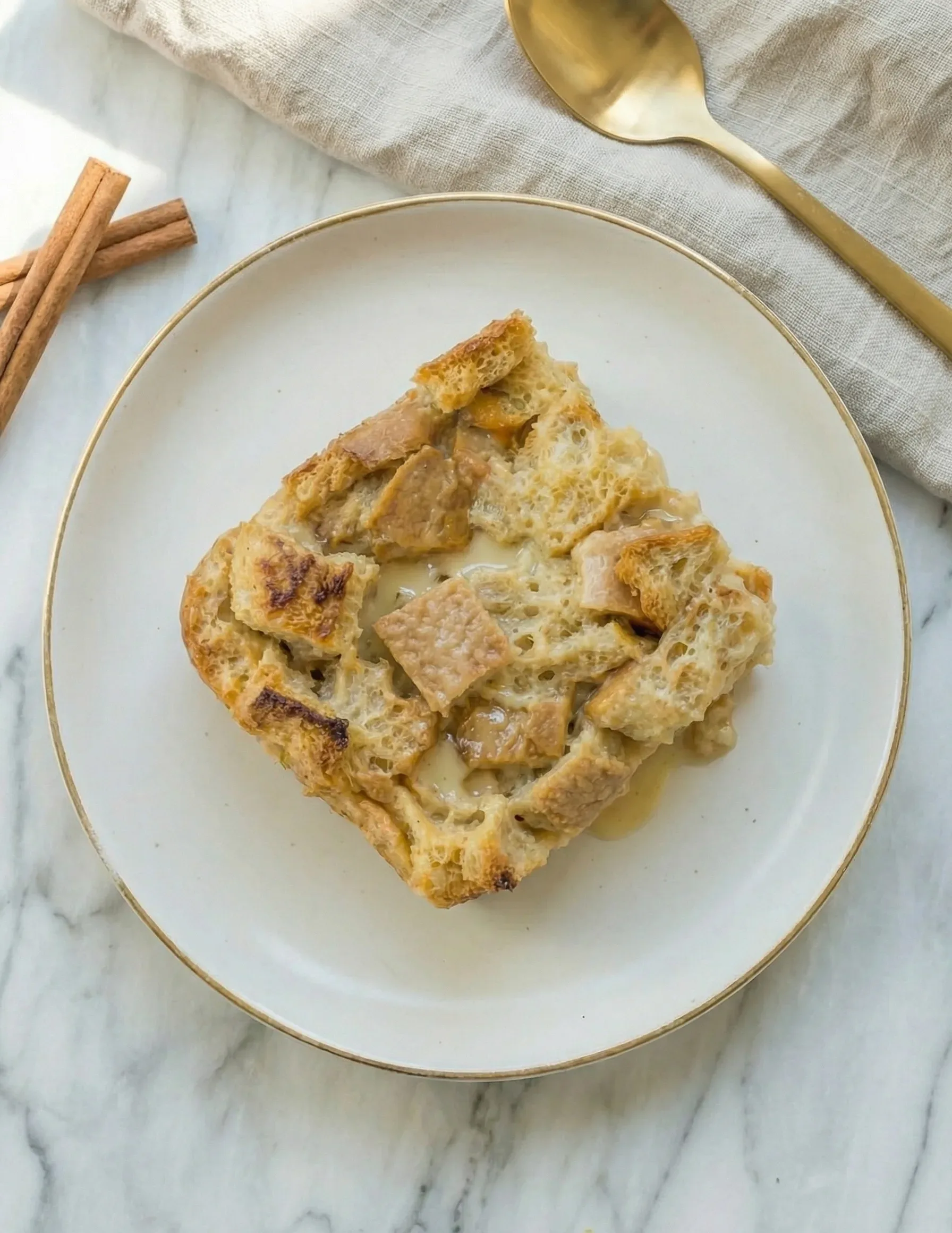 Single serving of bread pudding recipe on a white plate with vanilla sauce
