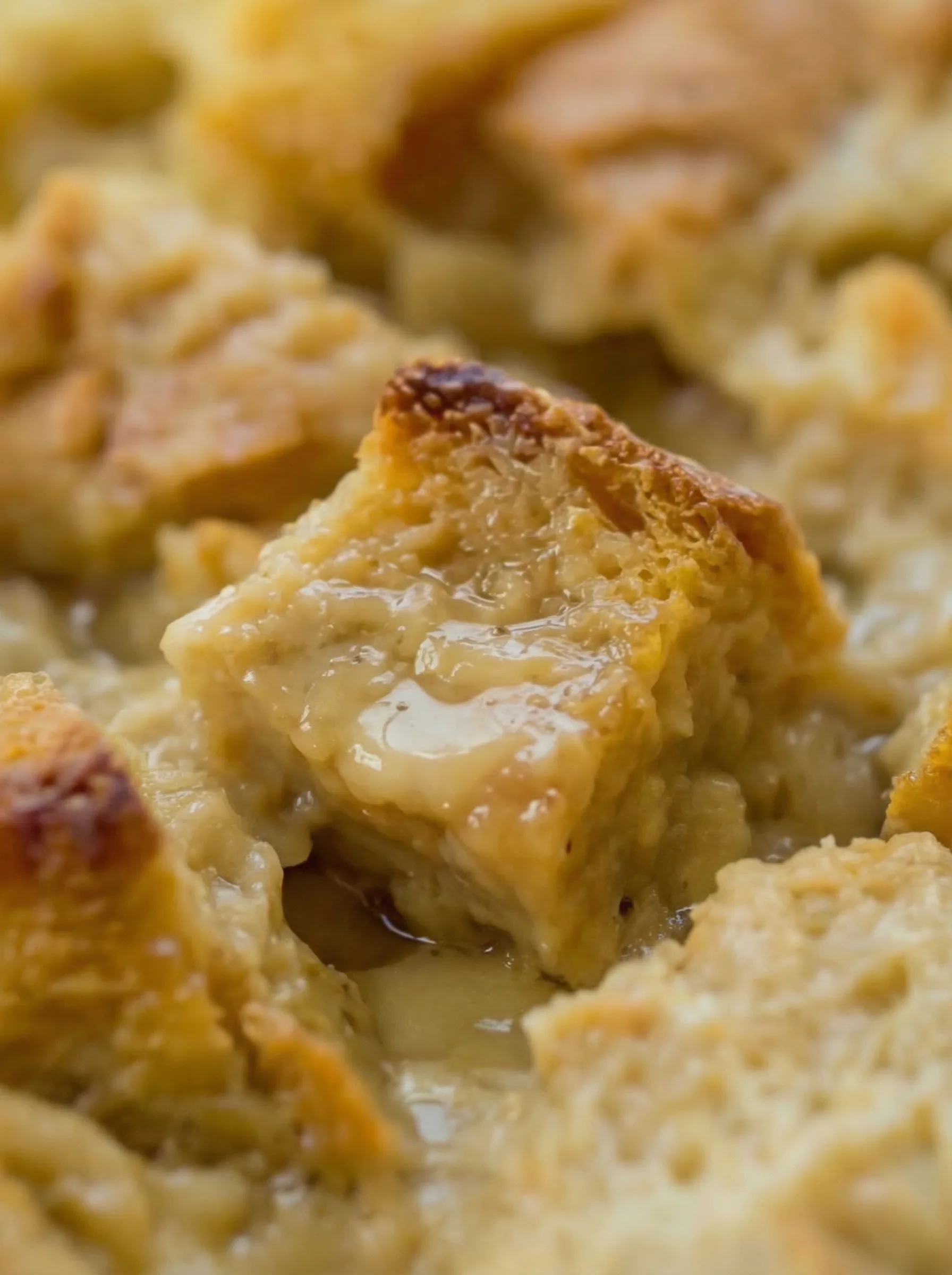 Close-up of creamy bread pudding texture with vanilla sauce soaking into the bread